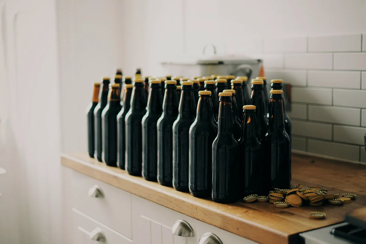 A row of dark glass bottles on a wooden shelf