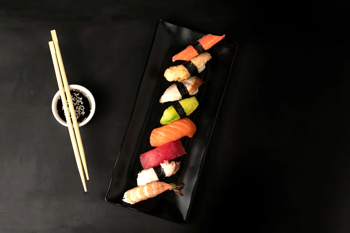 A row of nigiri laid along a dark rectangular board