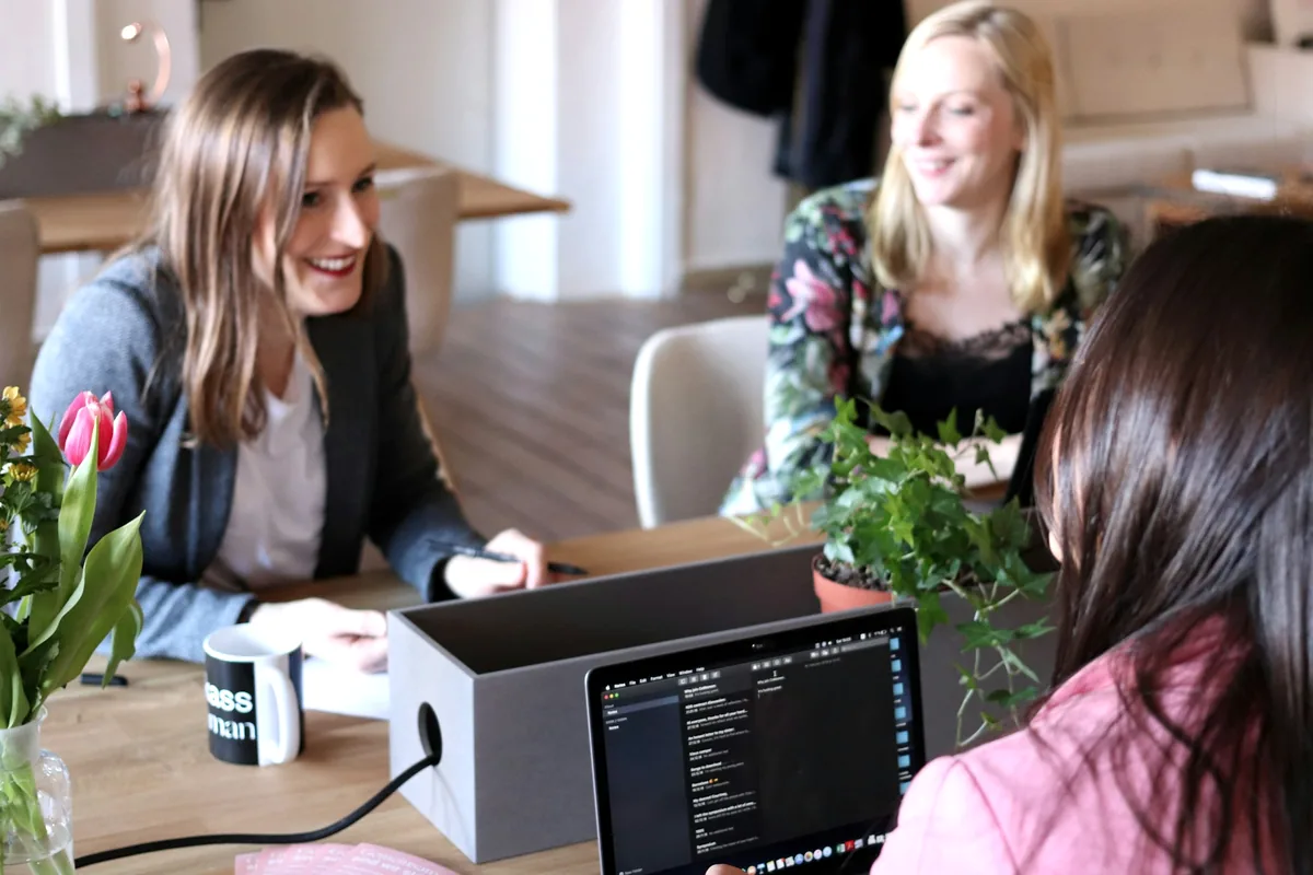 Three colleagues working and eating at a table with laptops