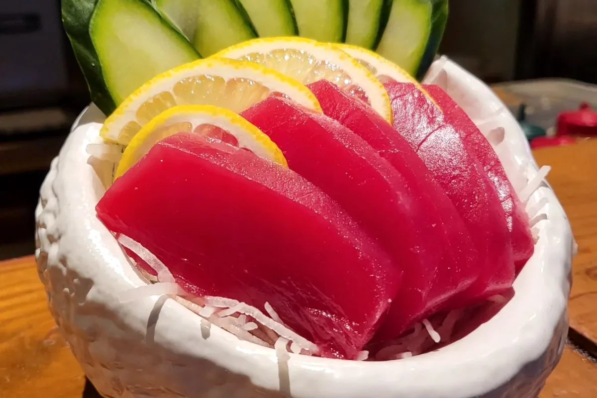 Sliced sashimi arranged on a plate with cucumber and lemon