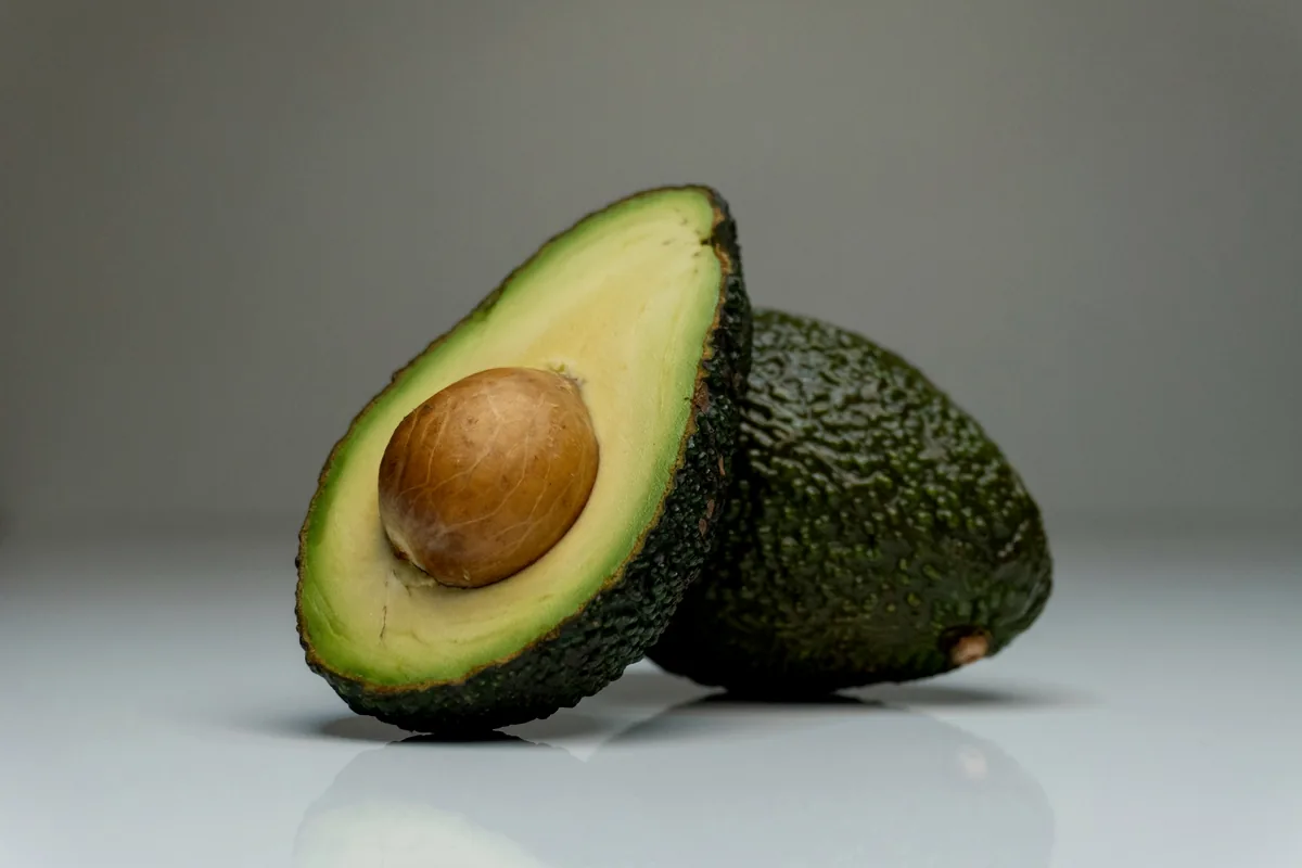 A halved avocado with the pit still in one side