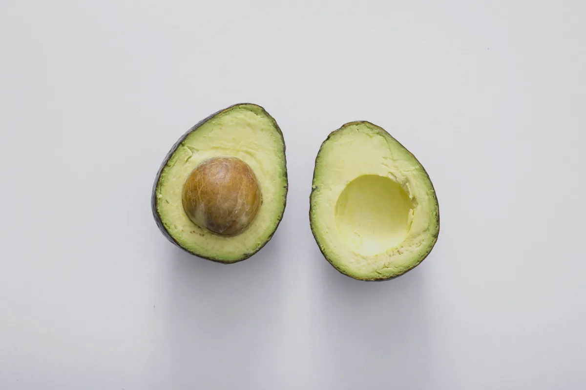 Two avocado halves on a plain white background