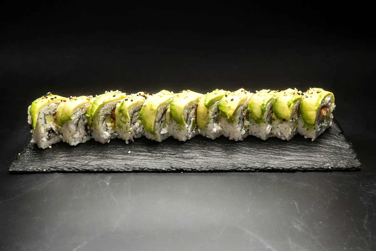 A row of avocado-filled rolls served on a dark slate board