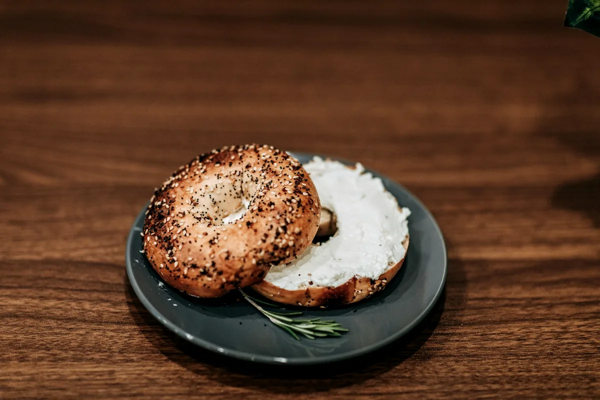 Two bagel halves spread with cream cheese on a dark plate