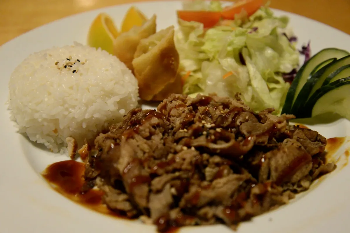 Beef Teriyaki with sliced beef, steamed rice, salad and pickled vegetables