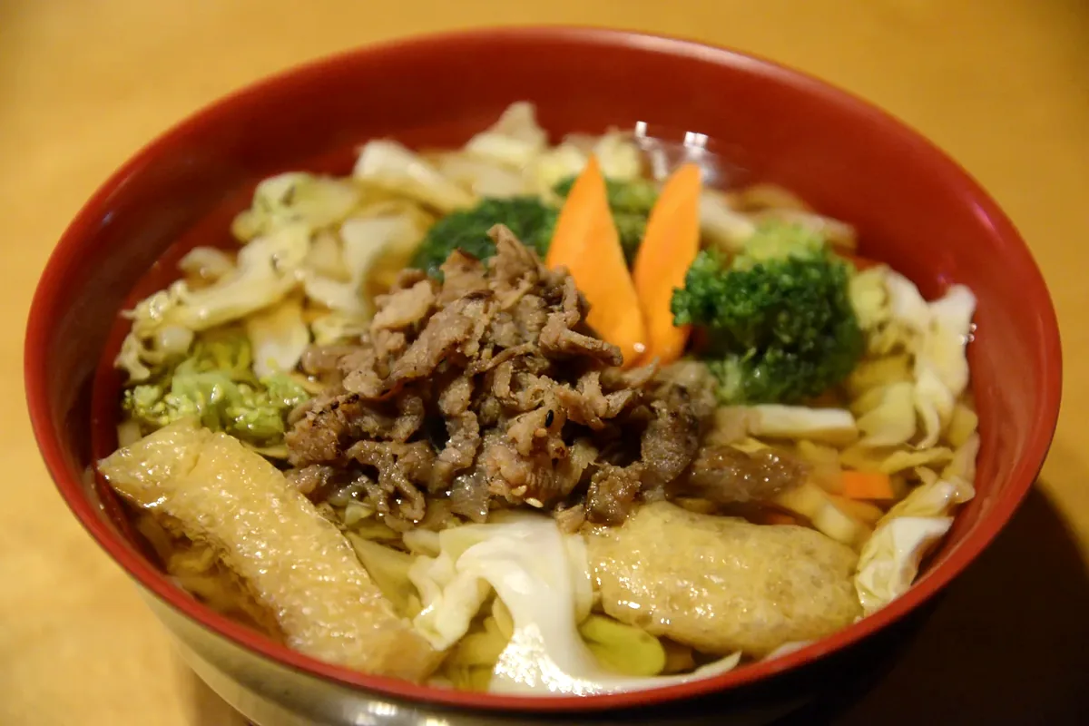 Beef Udon with sliced beef, cabbage, carrot and broccoli in broth