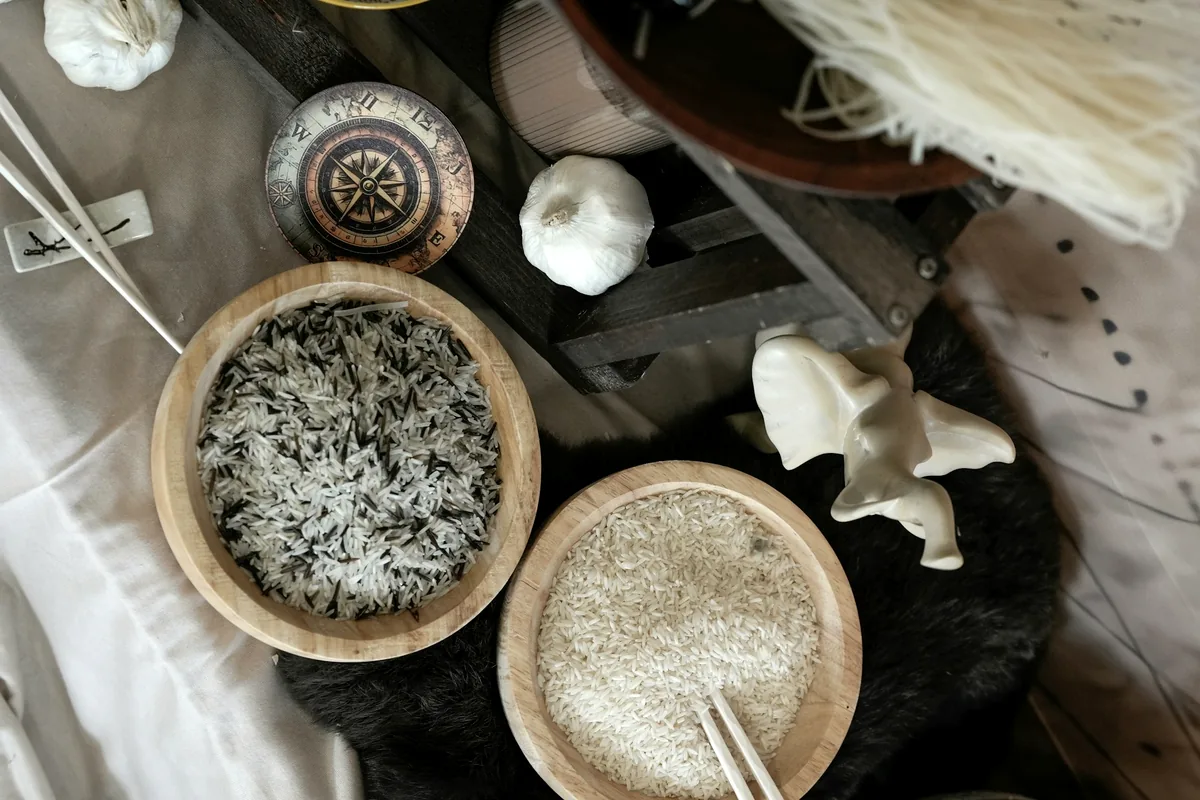 Small bowls of black and white sesame seeds on a wooden surface
