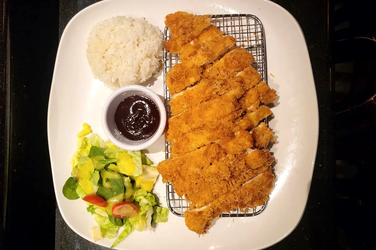 Chicken Katsu, a breaded fried cutlet sliced and served with rice and salad