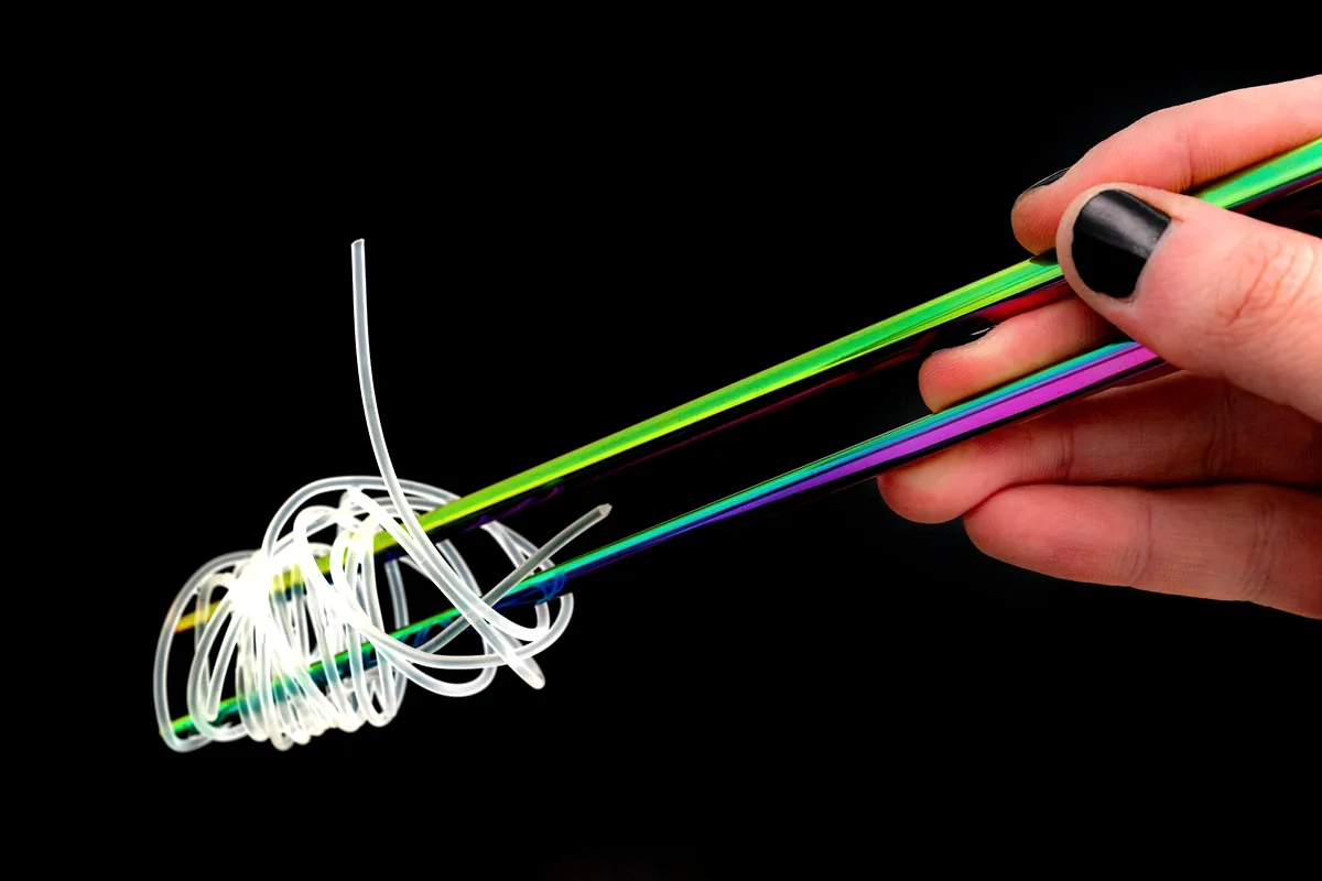 Brightly coloured chopsticks lifting a tangle of noodles