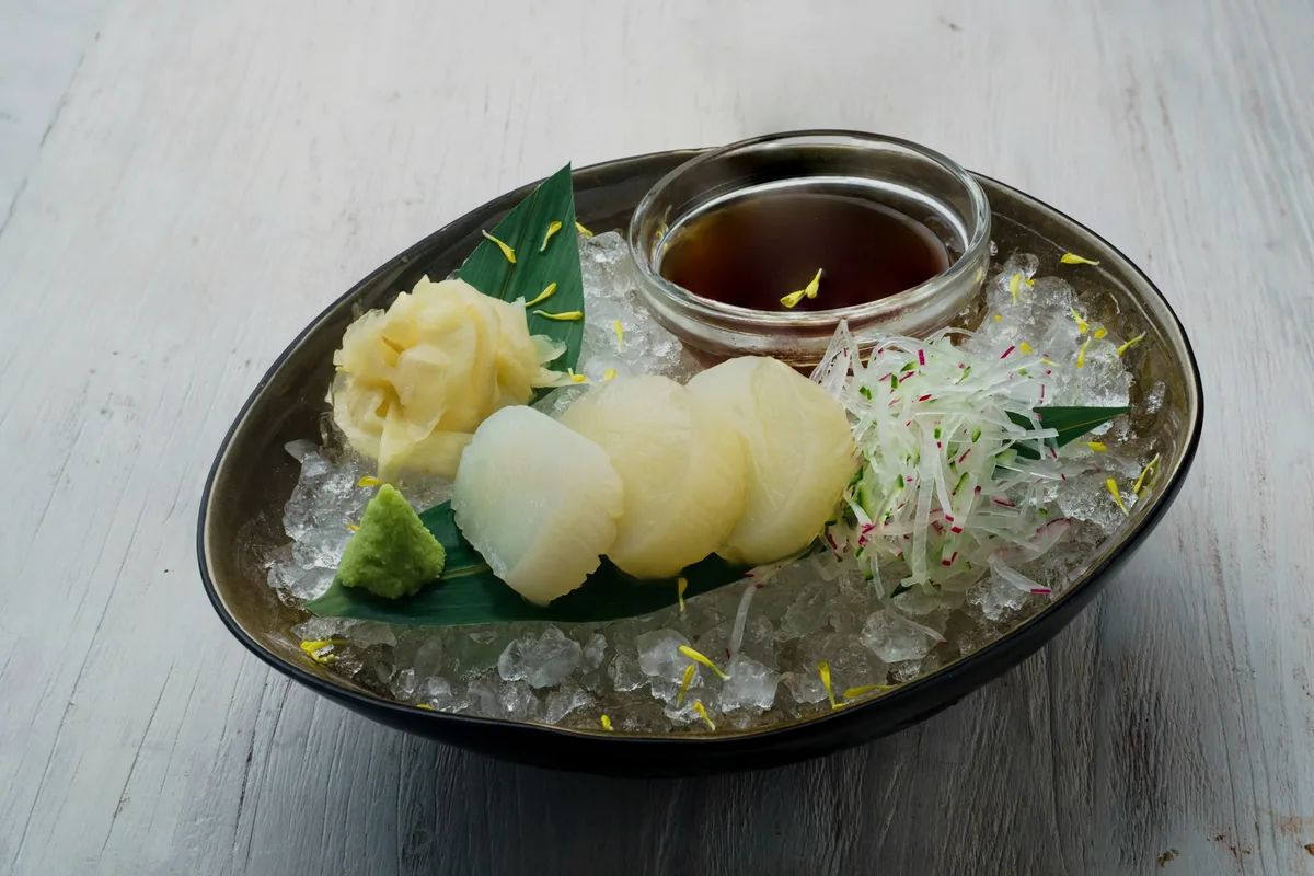 A plate of pickled ginger, green paste and shredded daikon arranged over ice