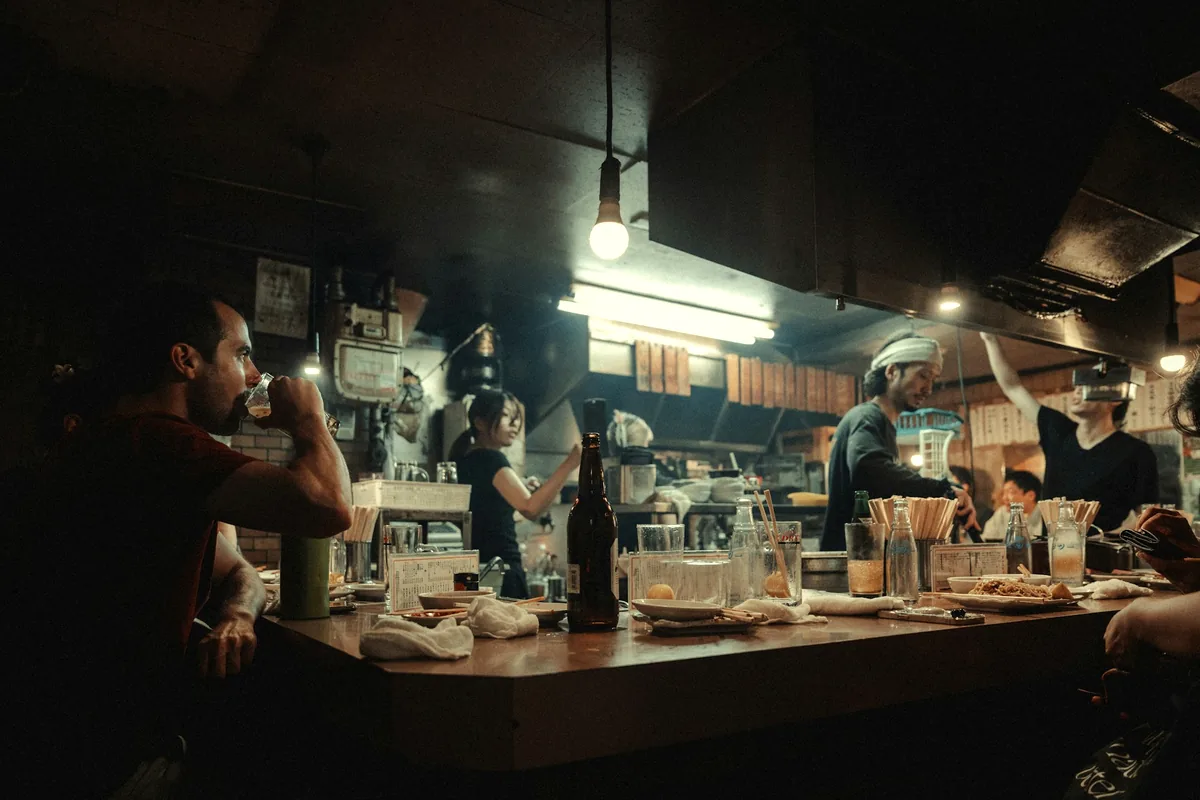 Diners seated along a warmly lit counter in the evening