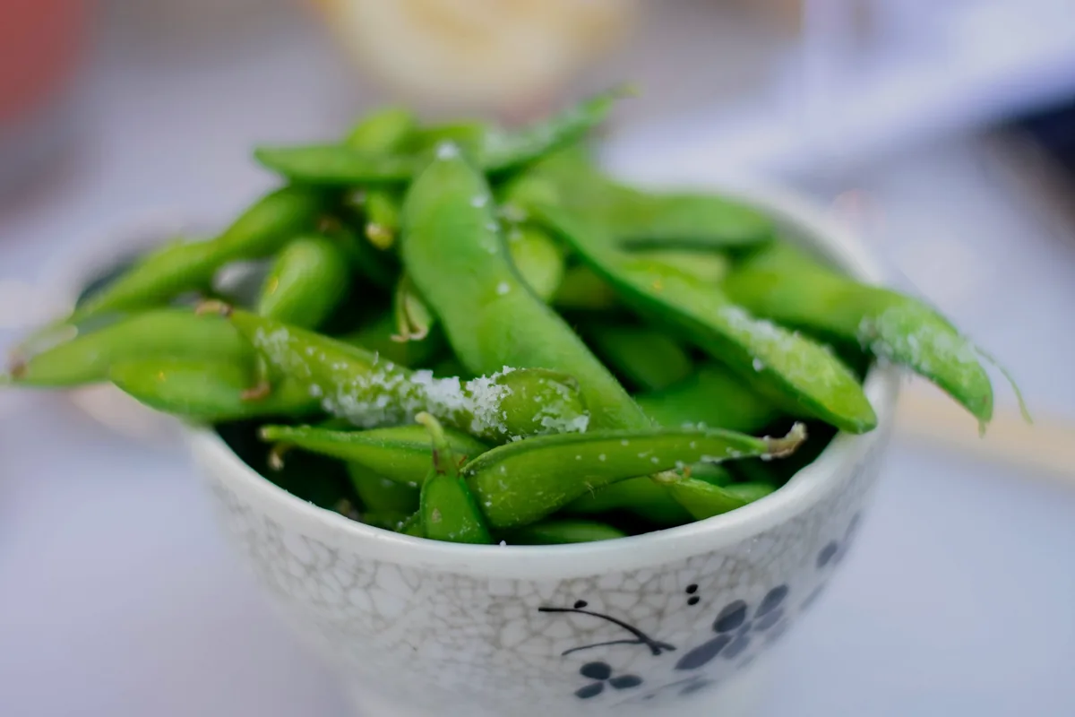Salted edamame pods heaped in a patterned bowl