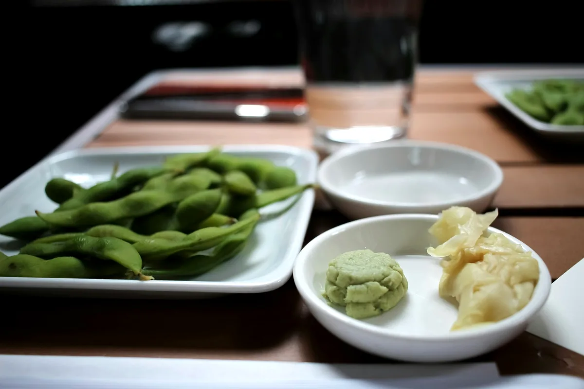 A dish of edamame on a set table with small side dishes