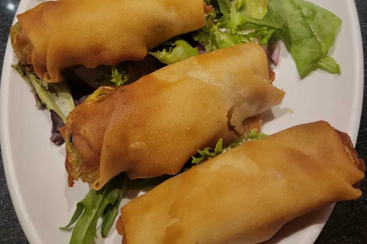 Three egg rolls served on shredded lettuce