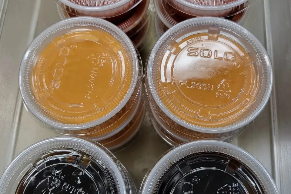 Small takeout cups of spicy mayo, eel sauce, hot sauce and ponzu