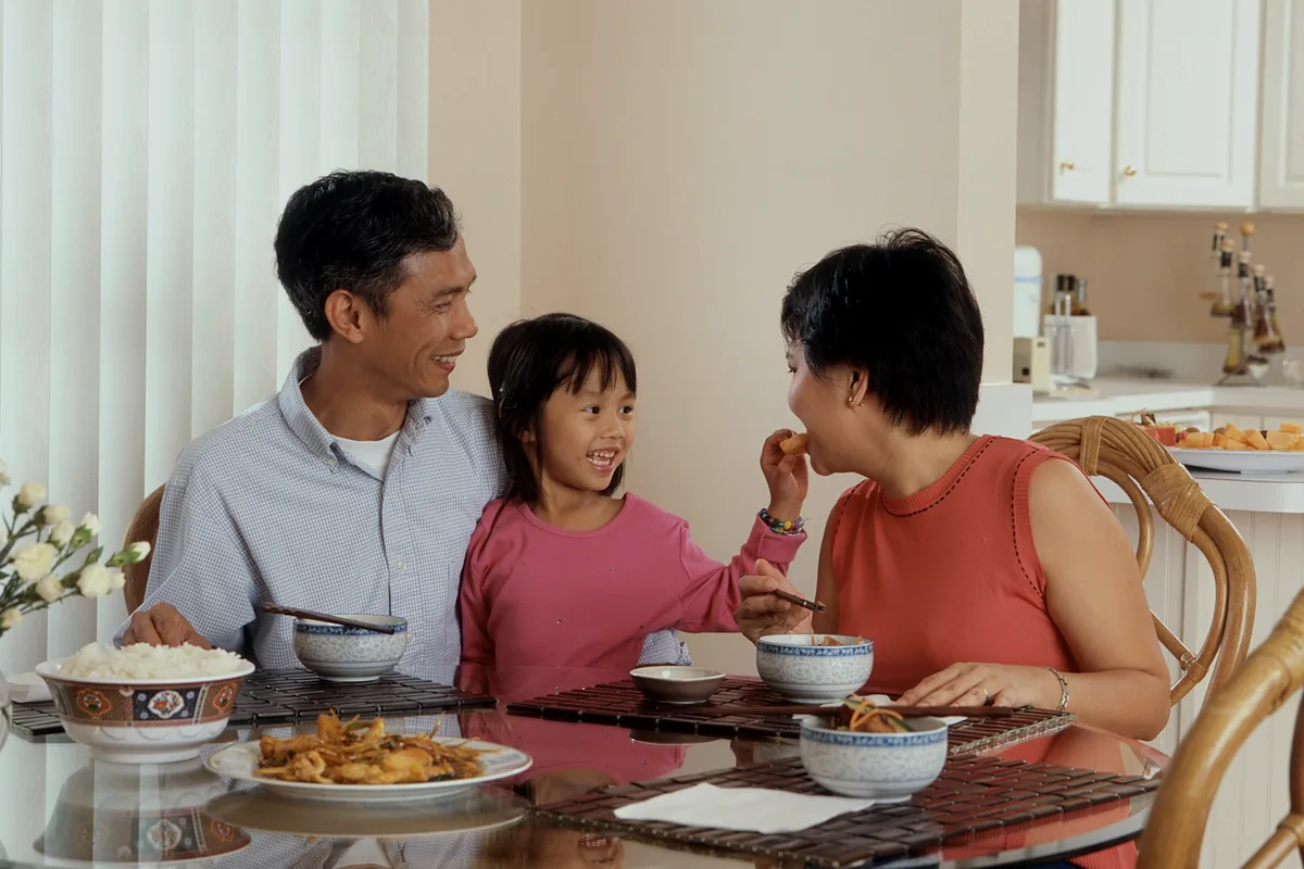 A family of four eating a meal together around a dining table