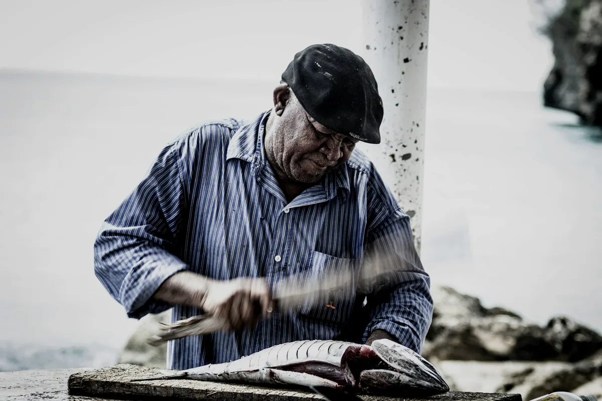 A fishmonger preparing fish behind a market counter