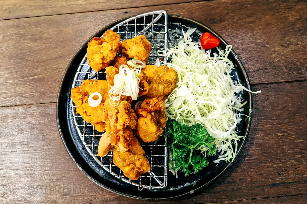 Fried pieces draining on a wire rack beside shredded cabbage