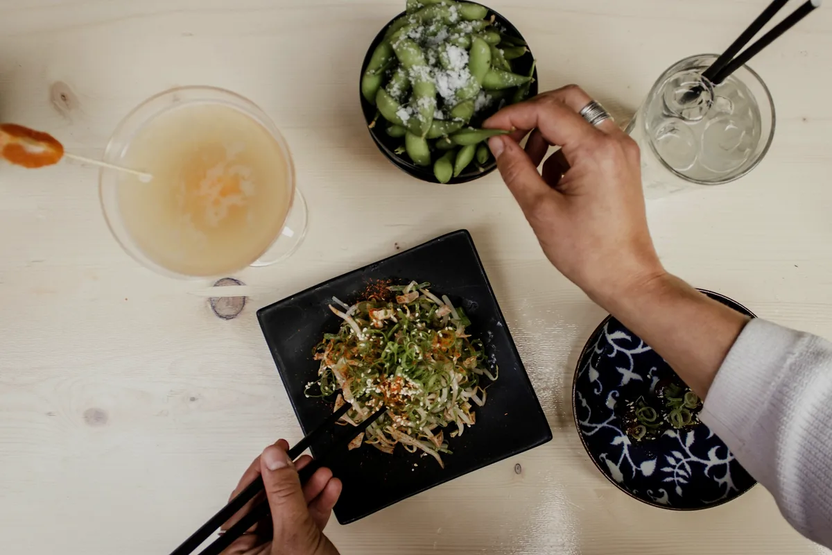 Several small plates being shared across a table by a group of diners