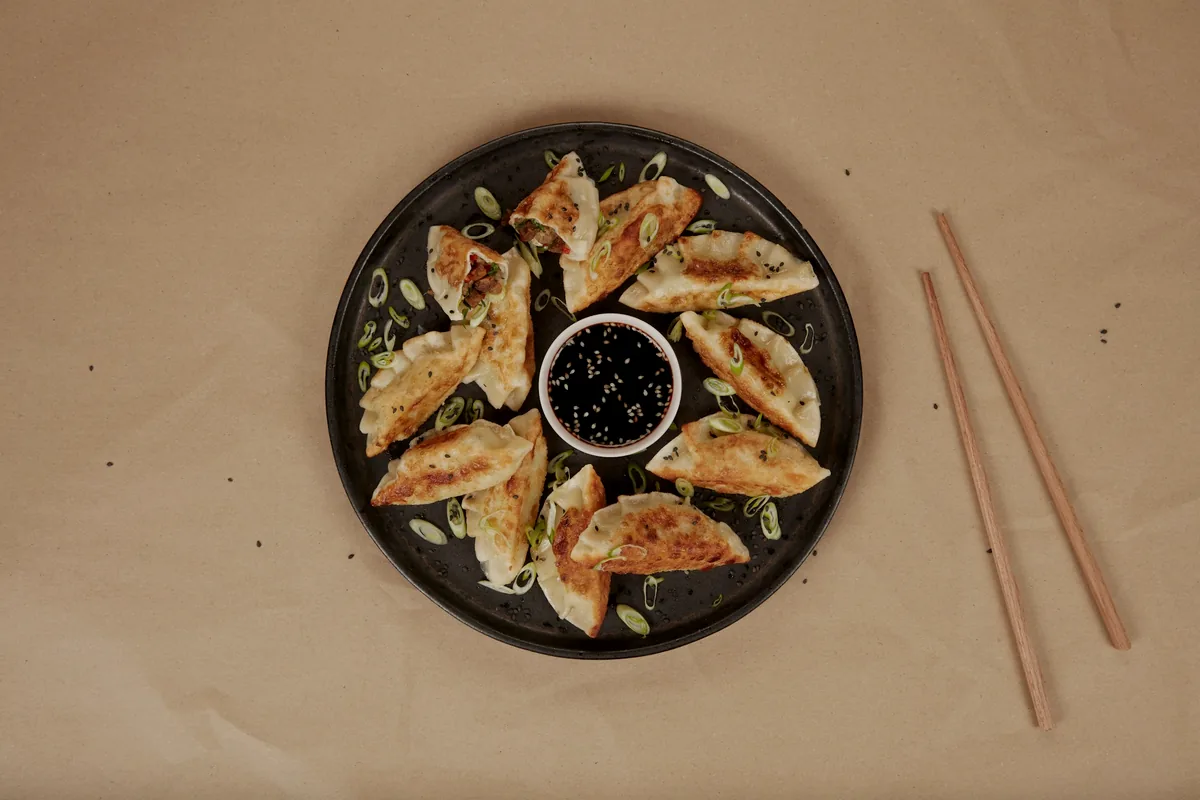 Dumplings arranged around a small dish of dark dipping sauce