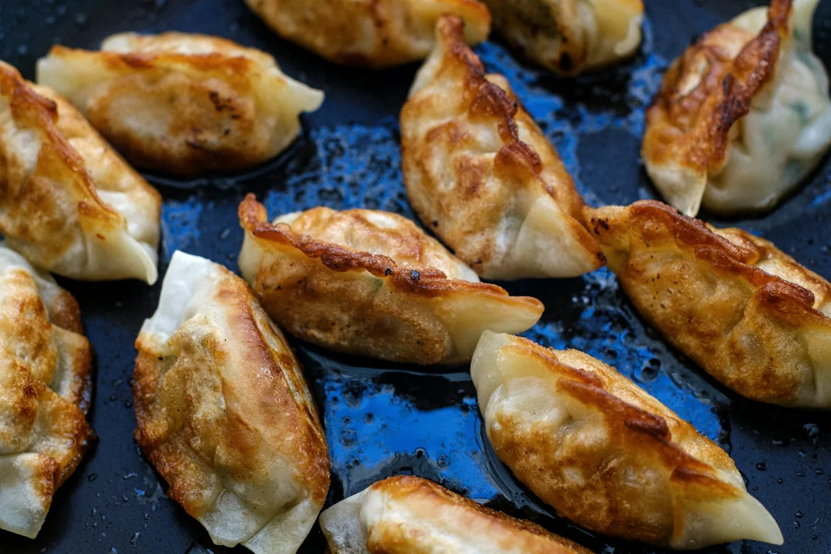 Dumplings frying in a pan, browned along their bases