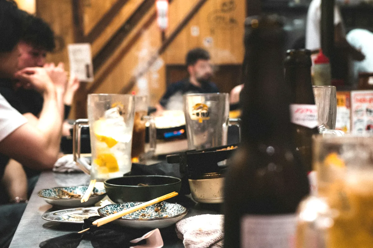 The interior of a small Japanese bar with diners and drinks at the counter