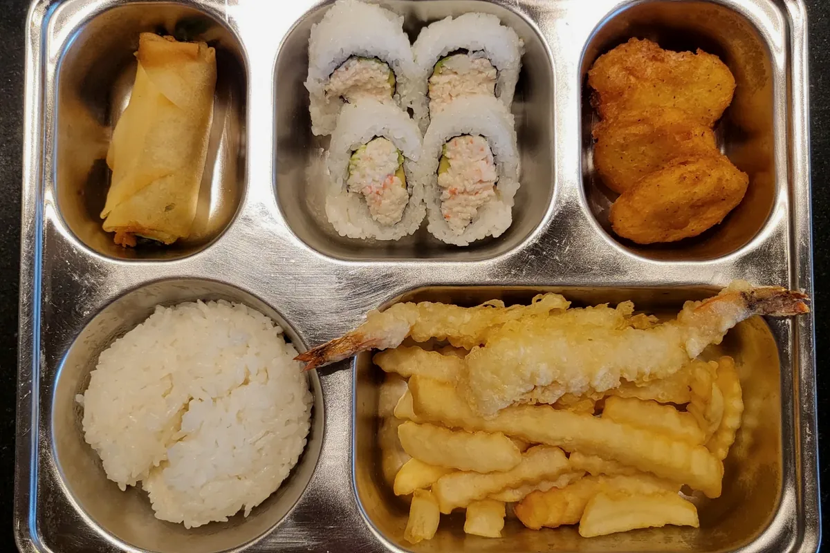 Kids Meal in a divided metal tray with an egg roll, a California roll, popcorn chicken and rice