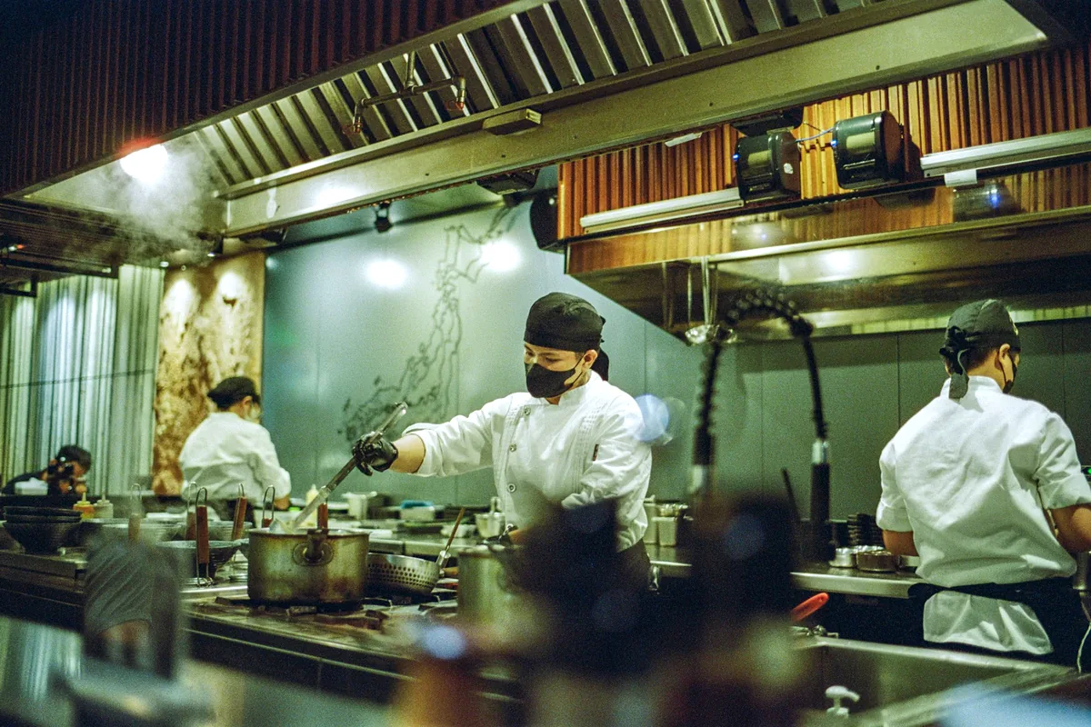 Cooks working along a stainless steel kitchen line