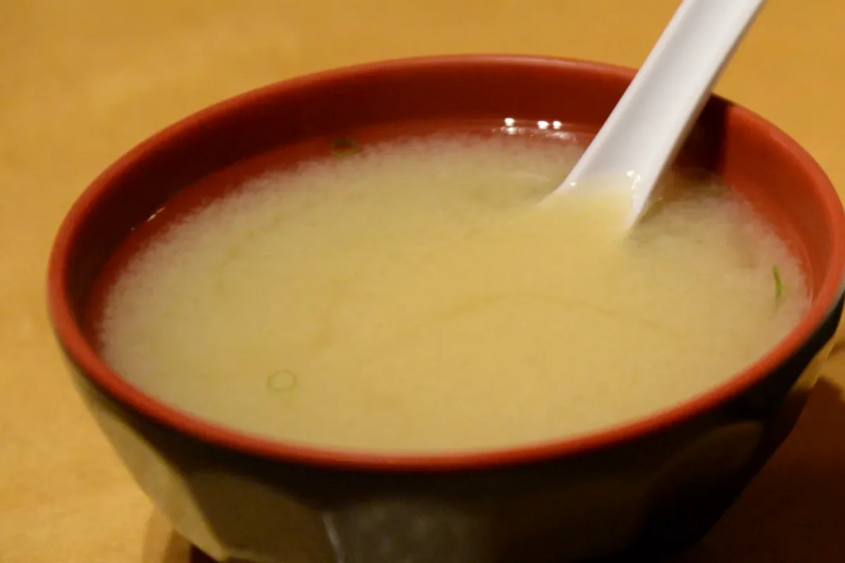 A bowl of miso soup with a soup spoon resting in it
