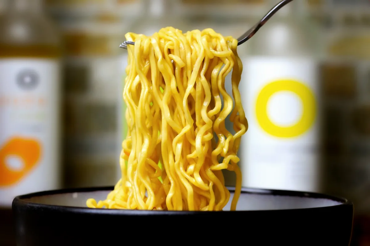 Yellow noodles lifted from a cooking pot with a fork