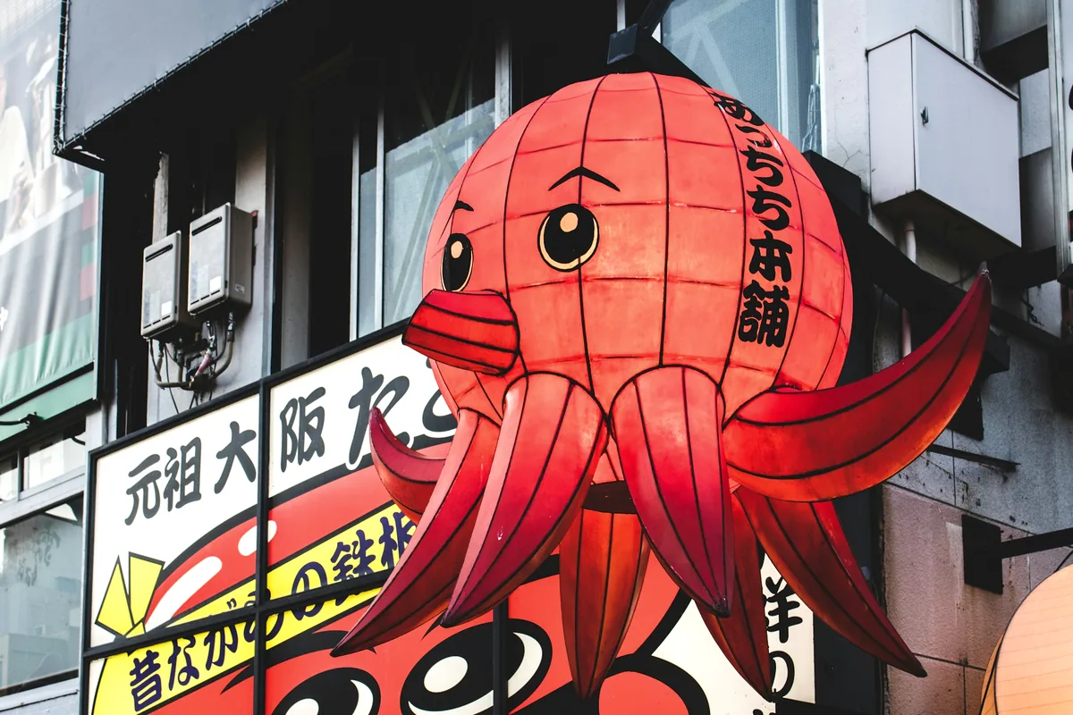 A large red octopus sculpture above a Japanese street food shopfront