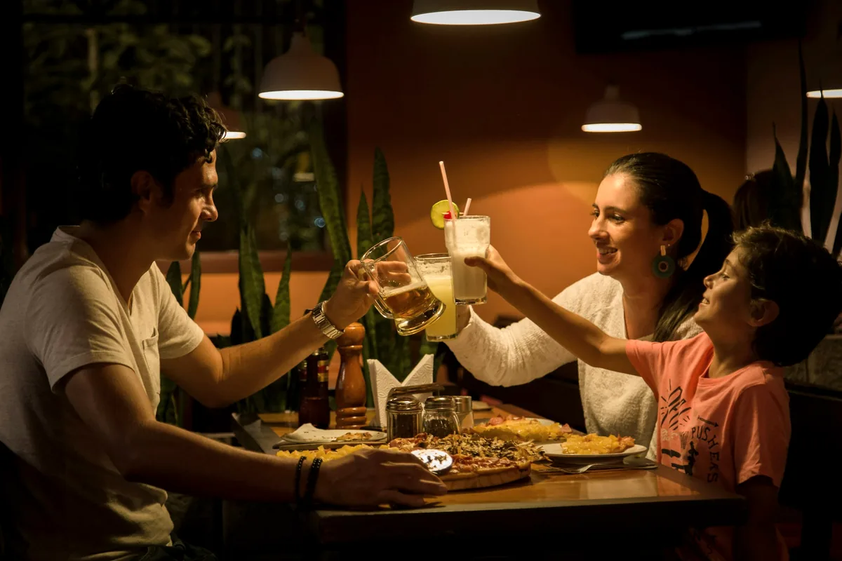 People around a restaurant table raising glasses over shared plates