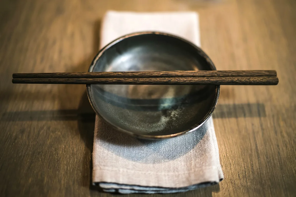 A pair of wooden chopsticks laid across the rim of a bowl