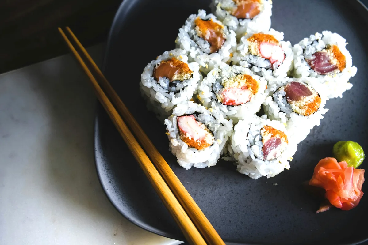 Cut rolls arranged on a dark plate with wasabi and pickled ginger