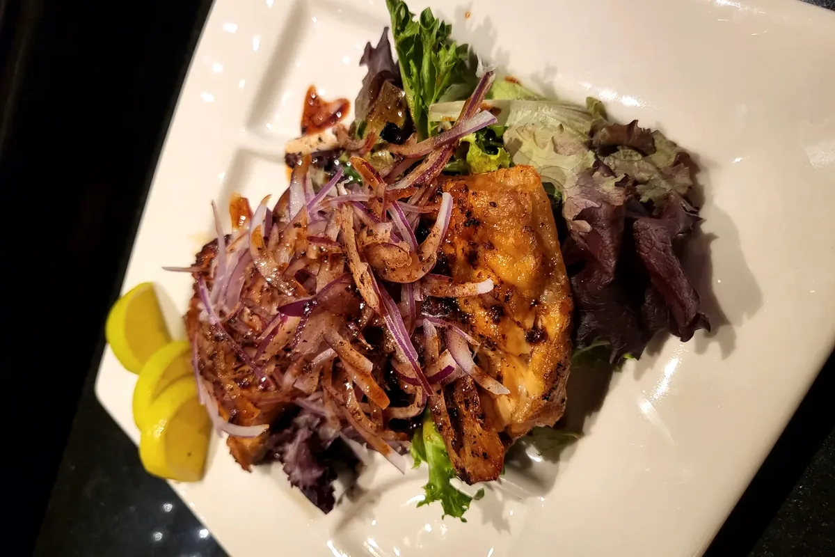 Salmon Collar, a baked salmon collar bone fillet served on a white plate