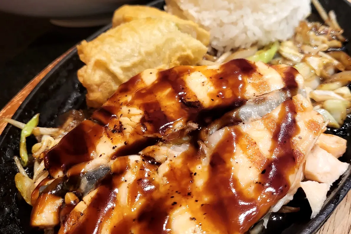 Salmon Teriyaki, glazed and sliced, plated over shredded cabbage