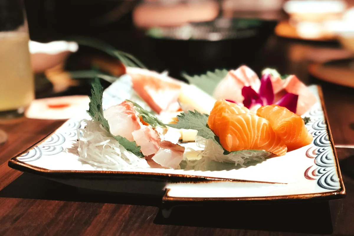 A plate of sliced sashimi served over shredded daikon with shiso leaf