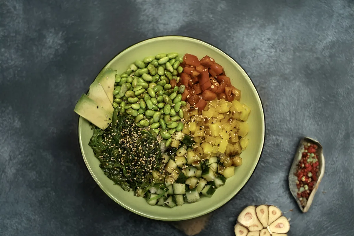 A bowl of rice arranged with vegetables, seeds and roe