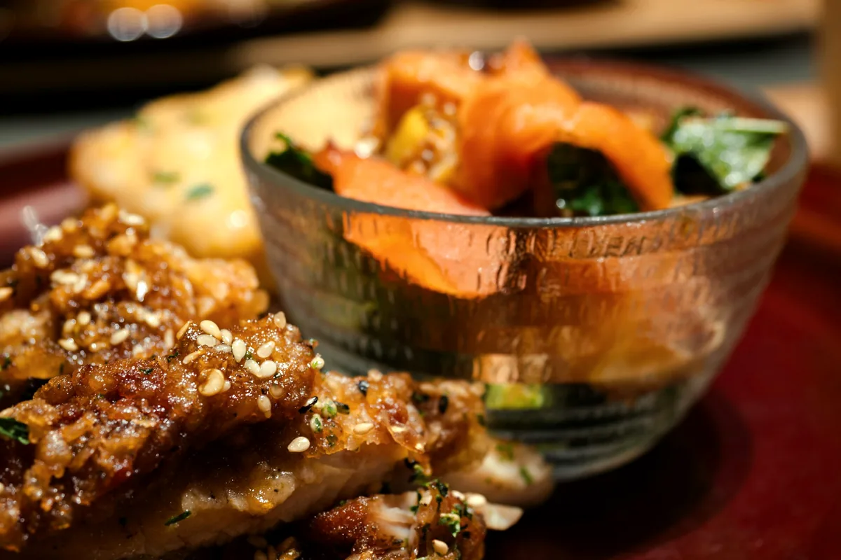 Glazed food scattered with sesame seeds in a glass bowl