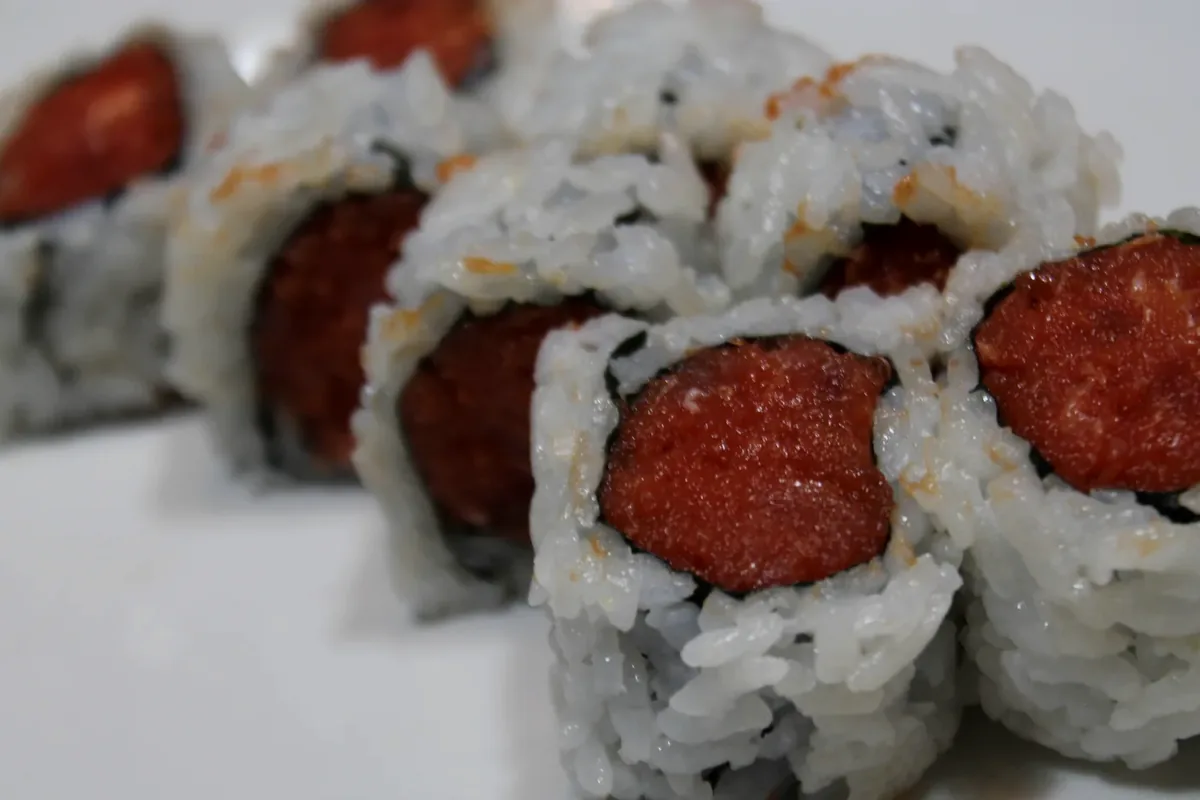Spicy Tuna Roll cut into pieces on a white plate