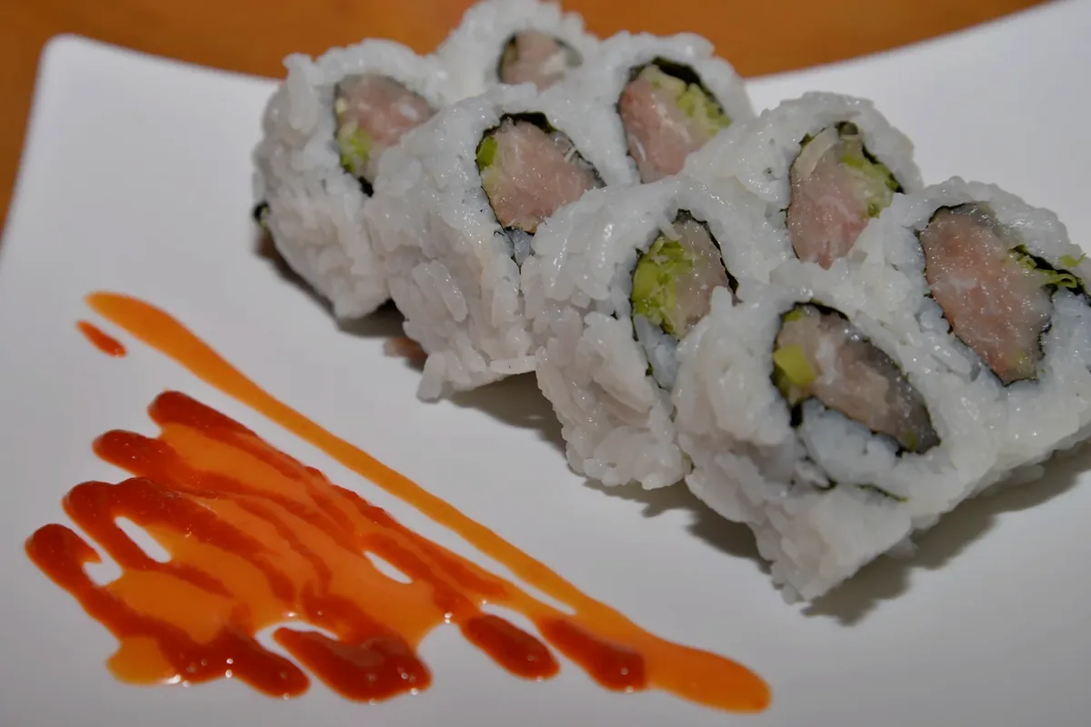 Spicy Yellowtail Roll cut into pieces on a white plate