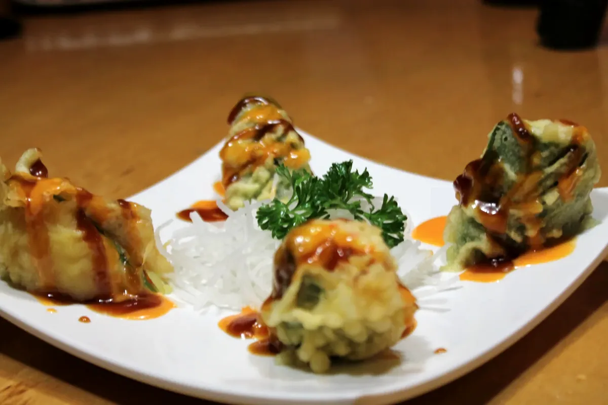 Four stuffed jalapenos, battered and fried, served on a white plate