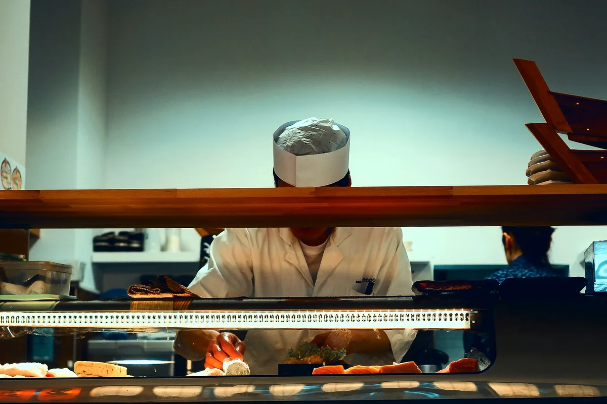 A refrigerated sushi counter case seen from a diner seat