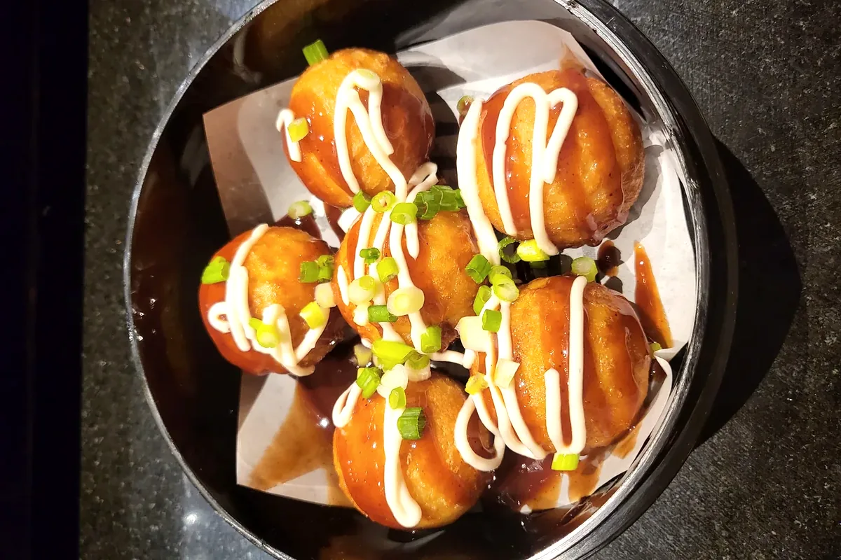 Takoyaki drizzled with sauce and mayonnaise, topped with green onion