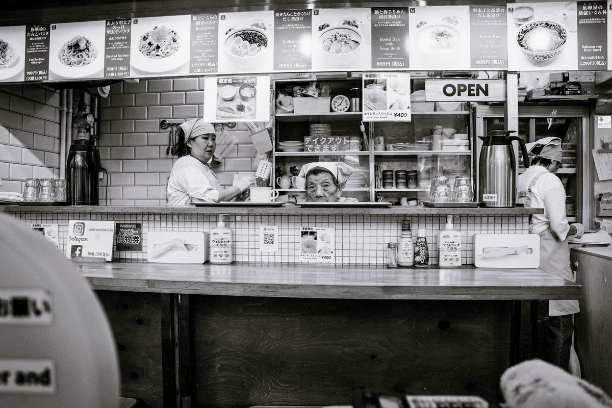 A black and white view along a narrow restaurant counter