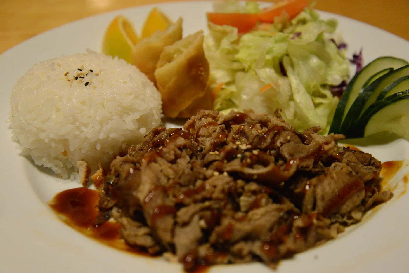 Beef Teriyaki with steamed rice and a side salad on a round plate