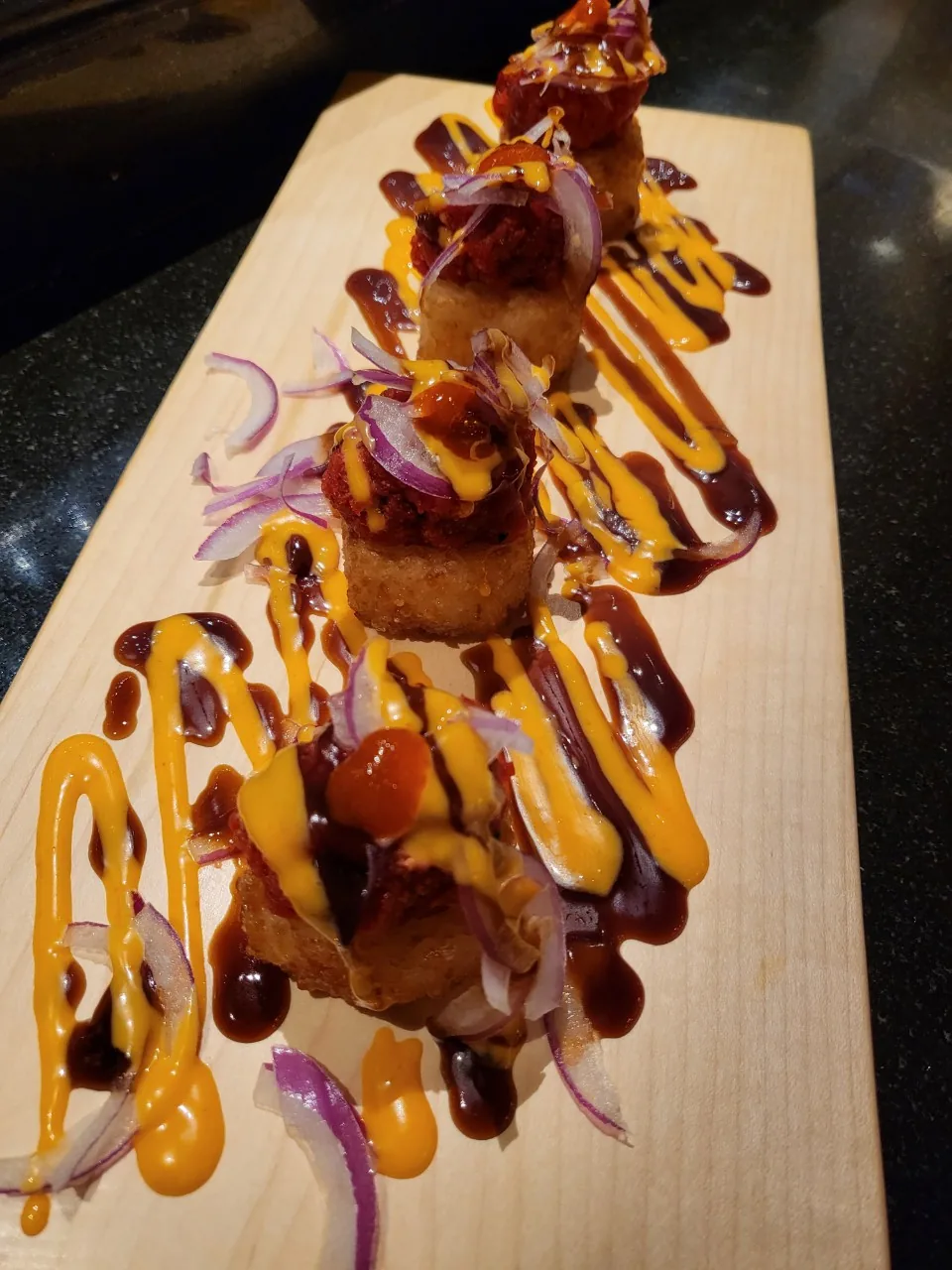 Crispy Rice on Spicy Tuna - four pieces on a wooden board with two sauces