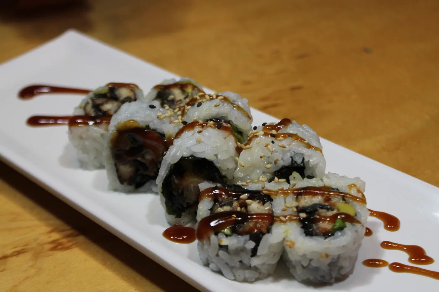 Eel Roll finished with eel sauce on a long white plate