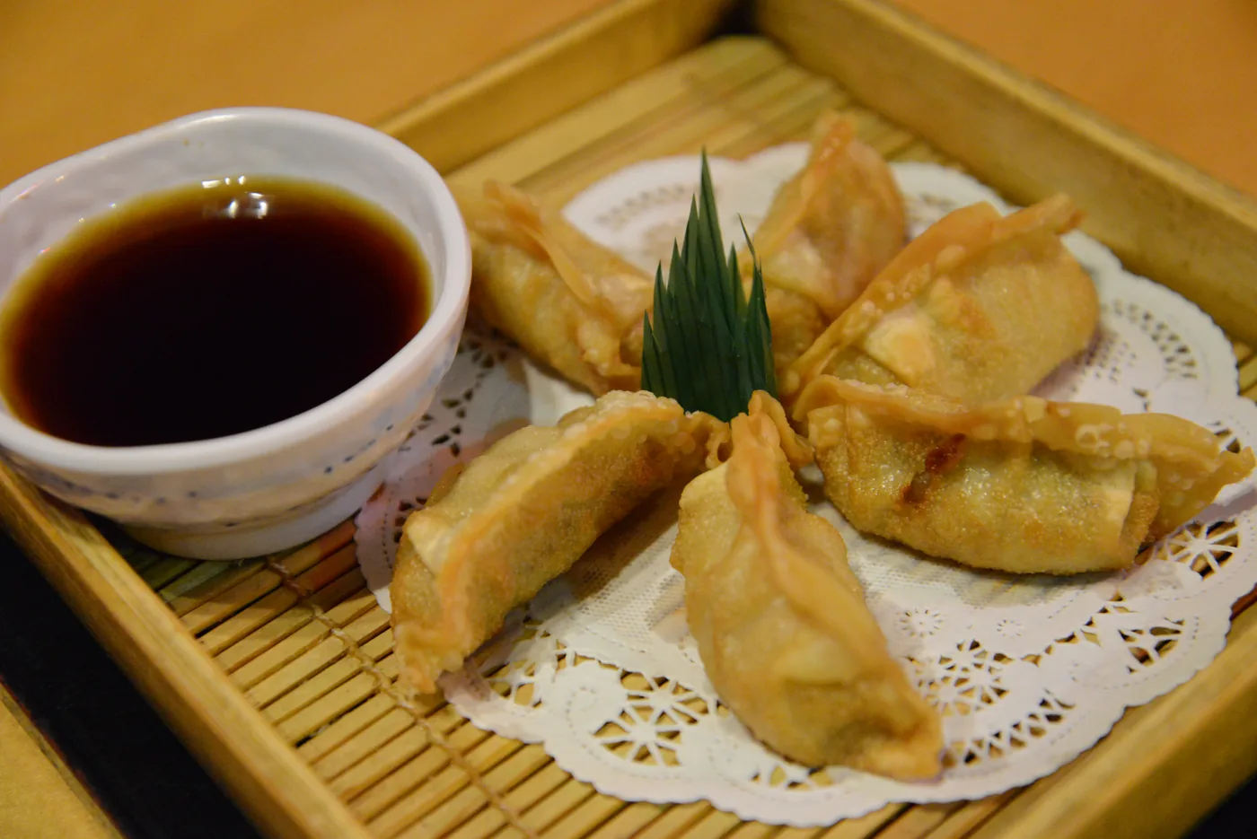 Gyoza on a bamboo tray with a bowl of dipping sauce