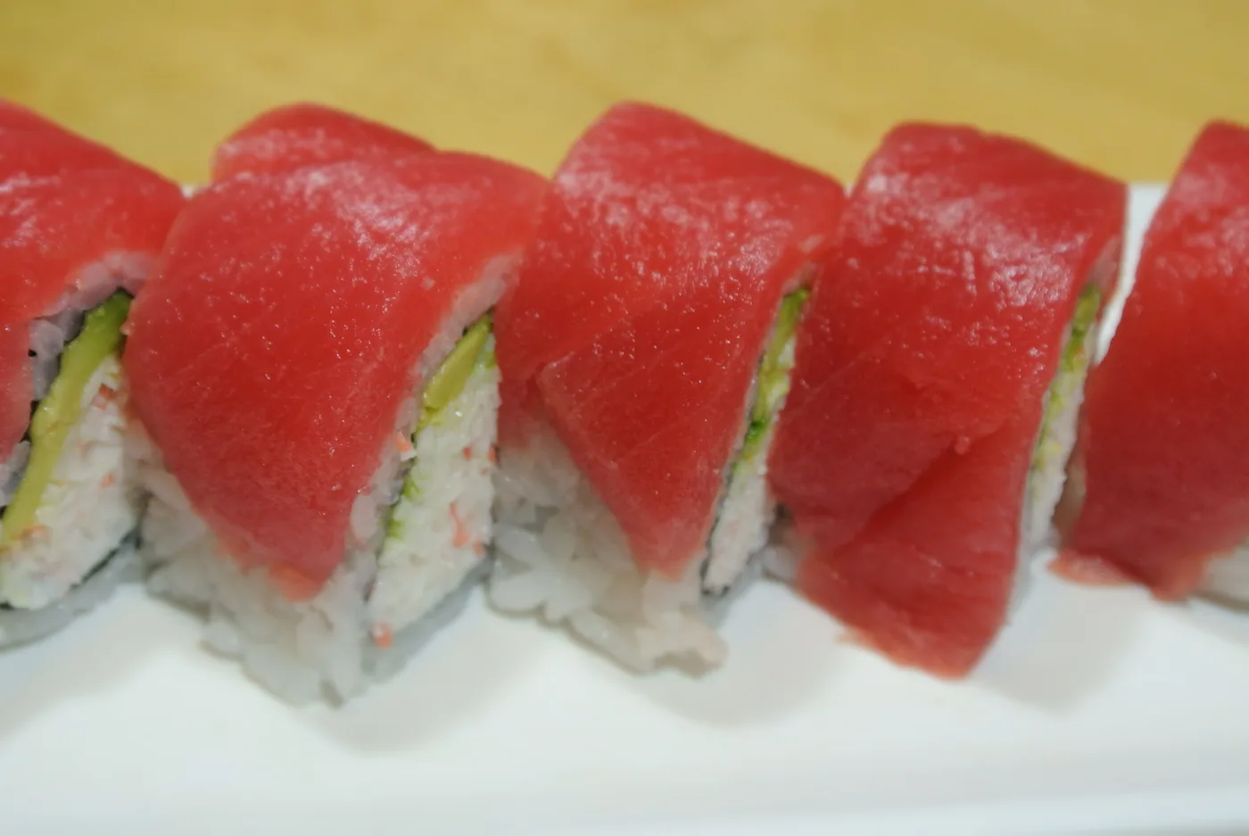 Hawaiian roll topped with slices of tuna on a white plate